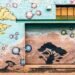 Colorful mural on a brick wall in Pasadena featuring trees and molecular shapes.